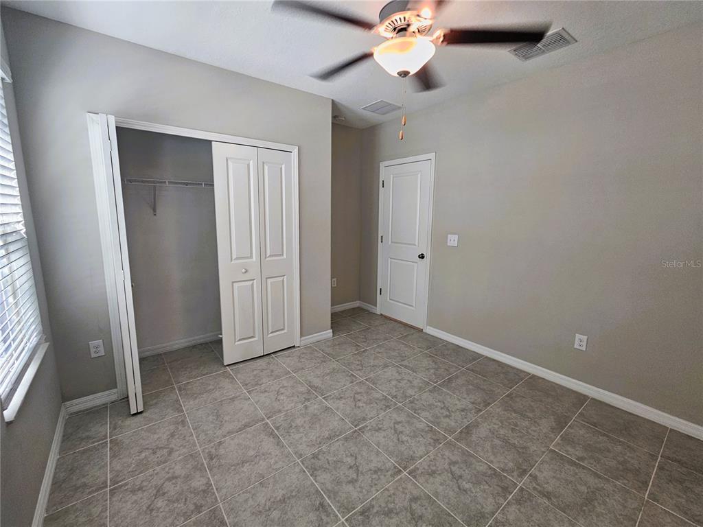 A bedroom with light gray walls, tile flooring, a ceiling fan, and a white closet — 6822 KING CREEK DRIVE, SUN CITY CENTER, FL