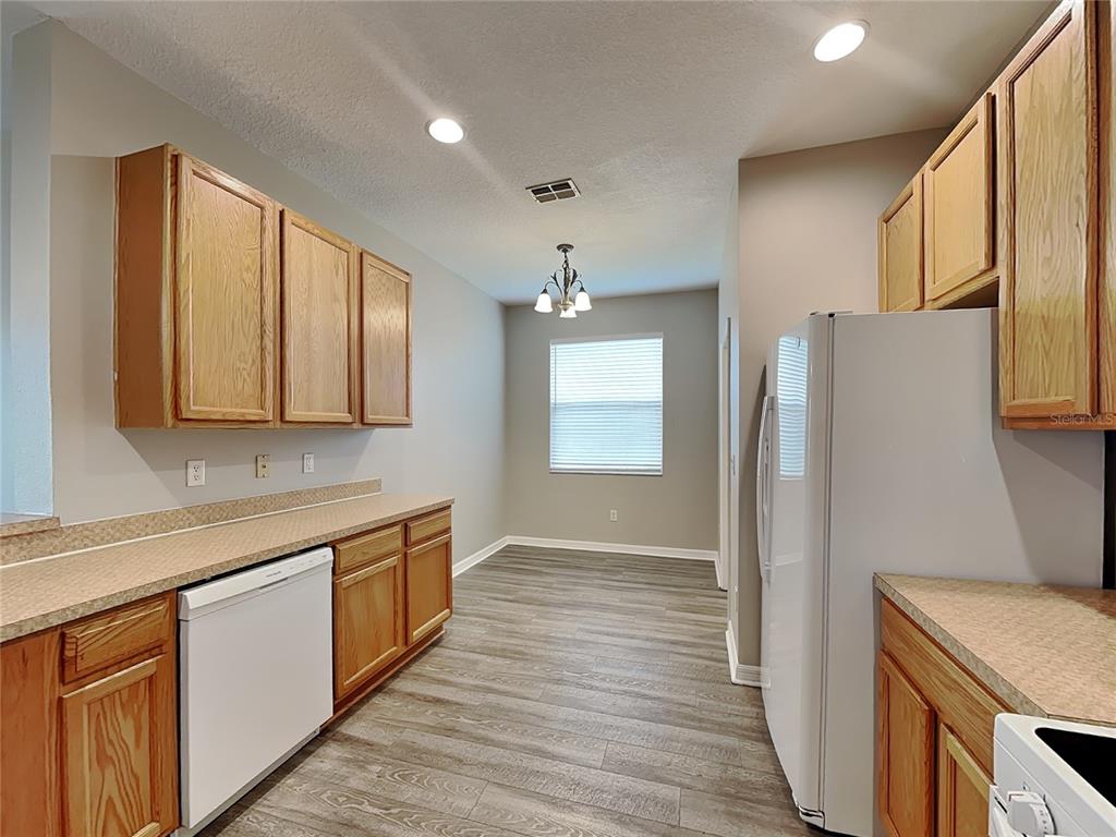 A kitchen with light wood cabinets, white appliances, and gray wood-look flooring — 221 FERN GULLEY DRIVE, SEFFNER, FL