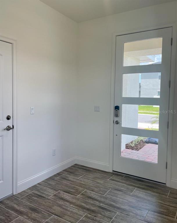 An entryway features wood-look tile flooring, white walls, a solid door, and a glass-paneled door — 3032 CRISPIN CIRCLE, ST CLOUD, FL