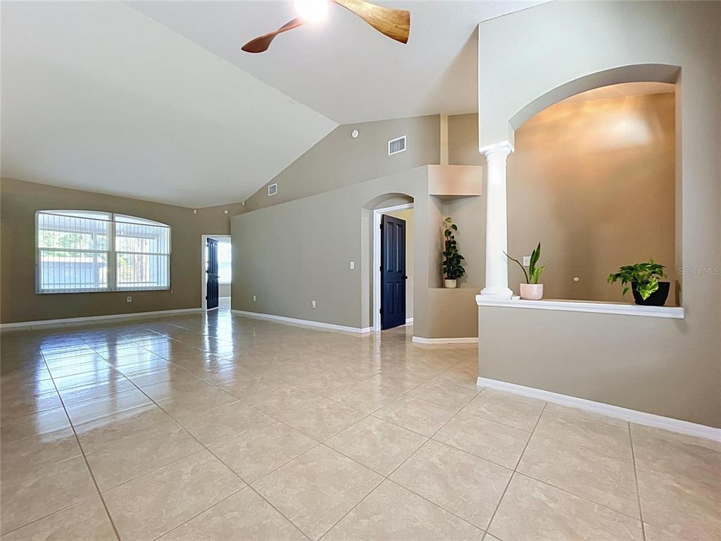 A spacious living area features vaulted ceilings, light tile flooring, and a decorative arched niche — 4209 AMBER RIDGE LANE, VALRICO, FL