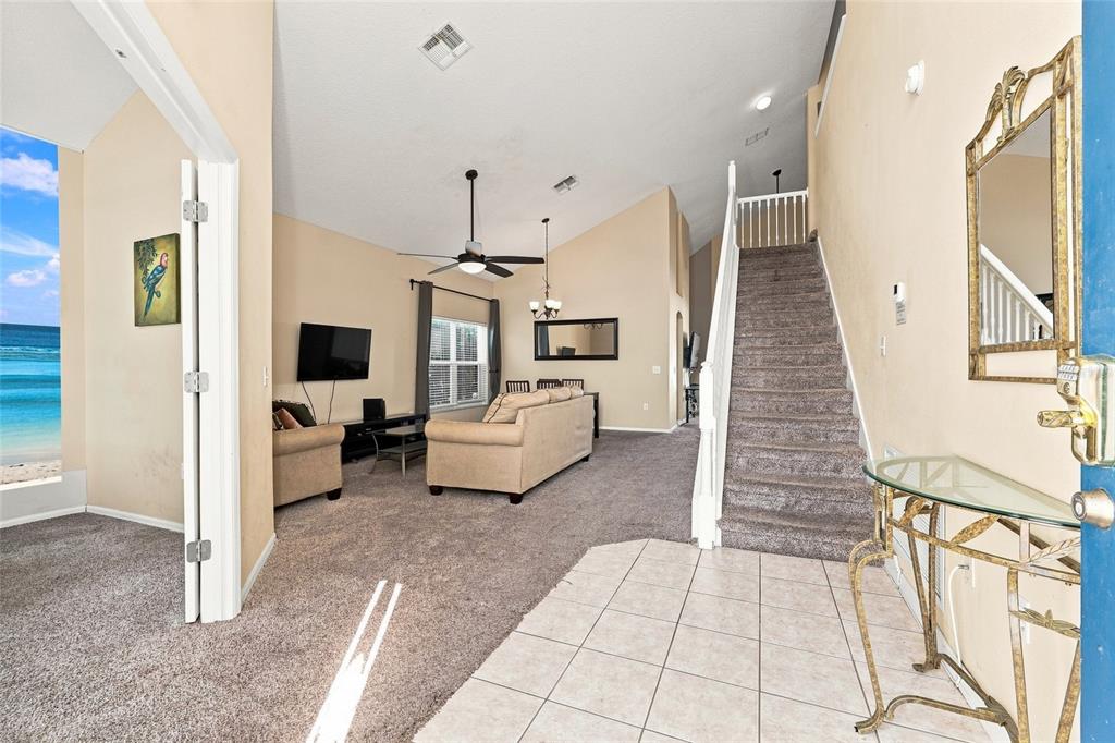 An interior view of a living room with carpeted stairs and a view of the ocean — 2915 BLOOMING ALAMANDA LOOP, KISSIMMEE, FL