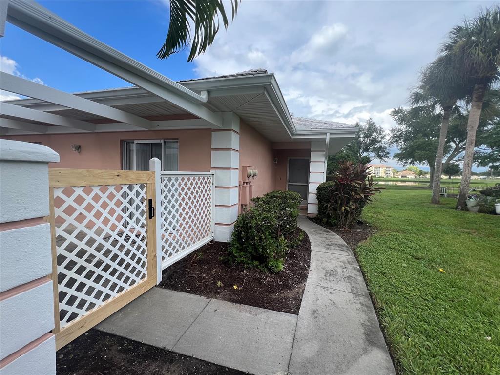 A palm tree and lush landscaping frame the exterior of a light-colored residential building — 338 CERROMAR WAY N UNIT 4, VENICE, FL