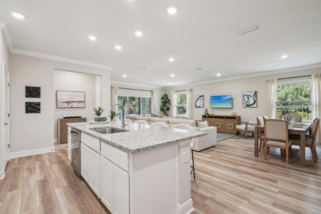 An open-concept kitchen with a granite island overlooks a living room and dining area — 13077 MEINERT AVENUE, BROOKSVILLE, FL