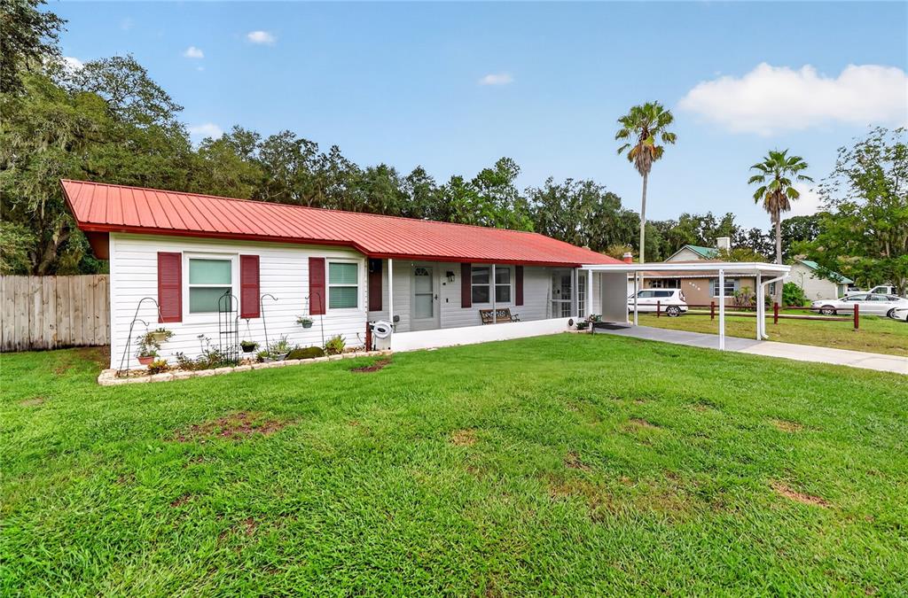 A single-story house with a red metal roof, white siding, and an attached carport — 6312 SWEETWATER DRIVE E, LAKELAND, FL