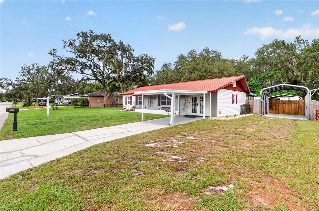 A single-story house with a red metal roof, white siding, and a covered front porch — 6312 SWEETWATER DRIVE E, LAKELAND, FL