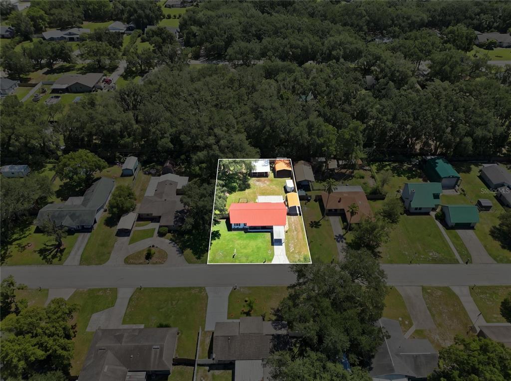 An aerial view shows a house with a red roof on a rectangular residential lot — 6312 SWEETWATER DRIVE E, LAKELAND, FL