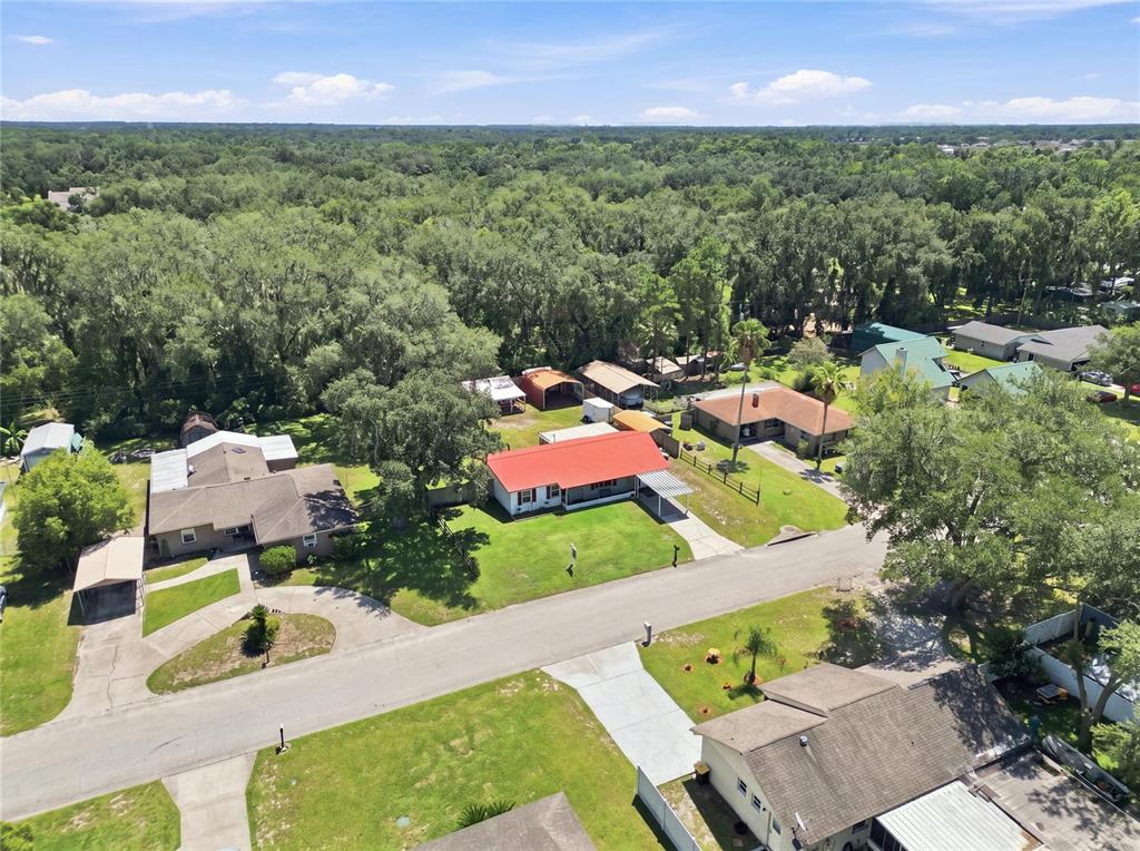 An aerial view shows several suburban houses with yards and driveways surrounded by dense trees — 6312 SWEETWATER DRIVE E, LAKELAND, FL