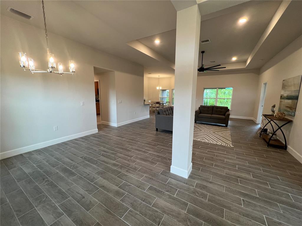 An open-concept living area features gray wood-look tile flooring, a central column, and recessed lighting — 27430 DEEP CREEK BOULEVARD, PUNTA GORDA, FL
