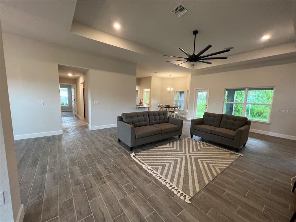 A living room features gray tile flooring, two sofas, a patterned rug, and a tray ceiling — 27430 DEEP CREEK BOULEVARD, PUNTA GORDA, FL