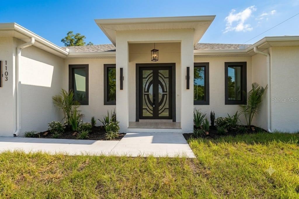 The exterior of a single-story house features a central entryway with double glass doors — 1103 ALPINE DRIVE, BRANDON, FL