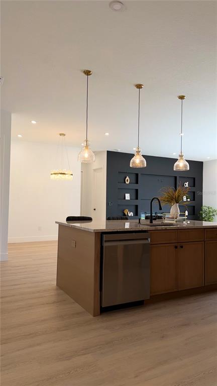 A modern kitchen features light wood cabinets, a central island with three stools, and pendant lighting — 1103 ALPINE DRIVE, BRANDON, FL