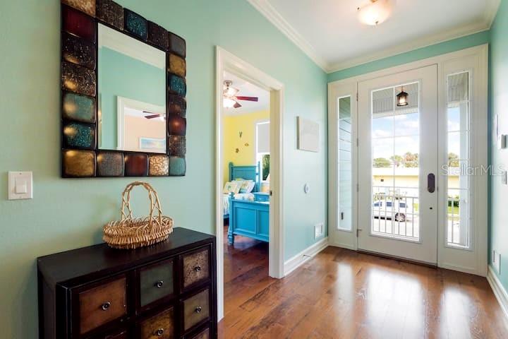 An entryway with a dark wood chest, a decorative mirror, and a view into a bedroom — 4808 GULF DRIVE UNIT B, HOLMES BEACH, FL