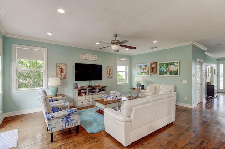 A living room features light blue walls, a white sofa, patterned armchair, and hardwood floors — 4808 GULF DRIVE UNIT B, HOLMES BEACH, FL