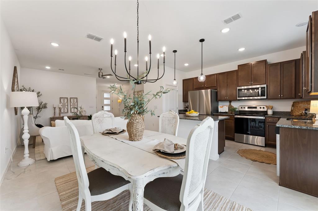 An open-concept living room and kitchen feature neutral furniture, tile flooring, and a ceiling fan — 1070 SPRING PALMS LOOP, ORLANDO, FL
