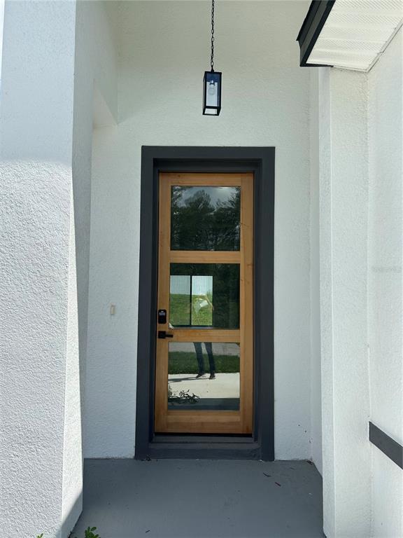 A wooden front door with glass panels is set within a white stucco entryway — 17145 SW 44TH CIRCLE, OCALA, FL