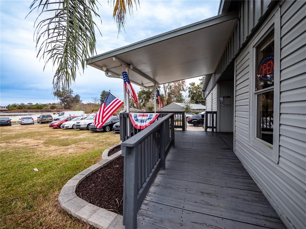 A wooden porch with a railing and American flag decorations overlooks a parking lot — 3001 S PINE AVENUE, OCALA, FL
