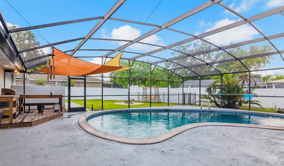 A screened-in pool enclosure features a concrete deck, a wooden grill station, and a sail — 105 SPRING COVE TRAIL, ALTAMONTE SPRINGS, FL