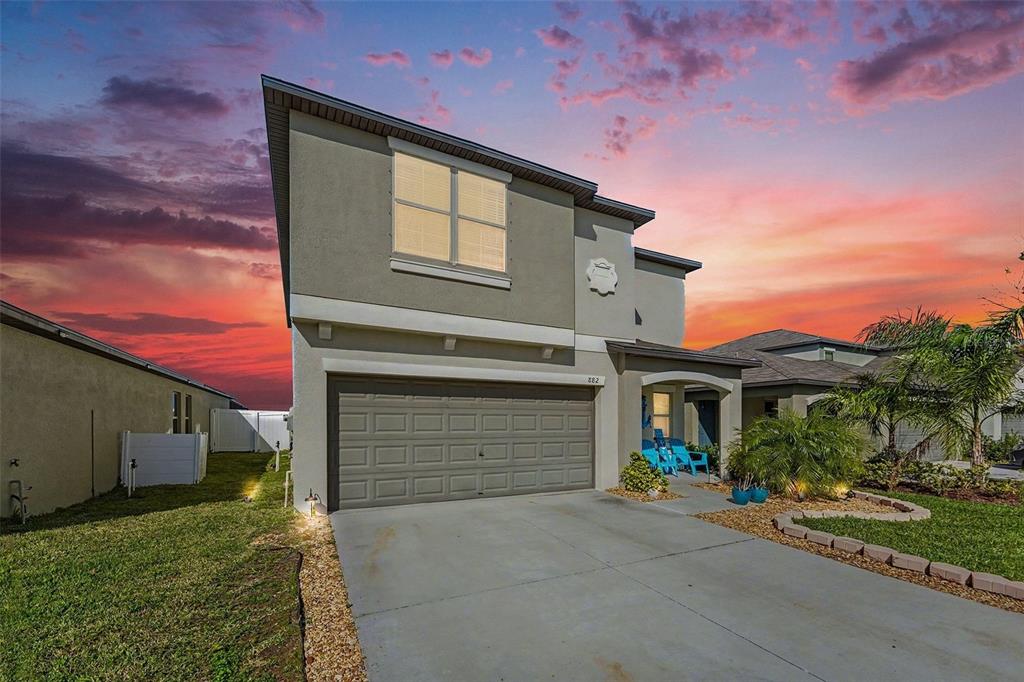 A two-story suburban house with a gray stucco exterior and a two-car garage — 882 OLIVE CONCH STREET, RUSKIN, FL