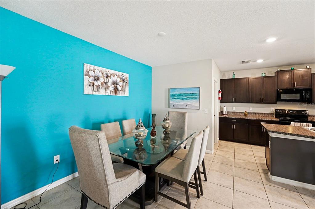 A dining area with a glass table, upholstered chairs, and a bright blue accent wall — 882 OLIVE CONCH STREET, RUSKIN, FL