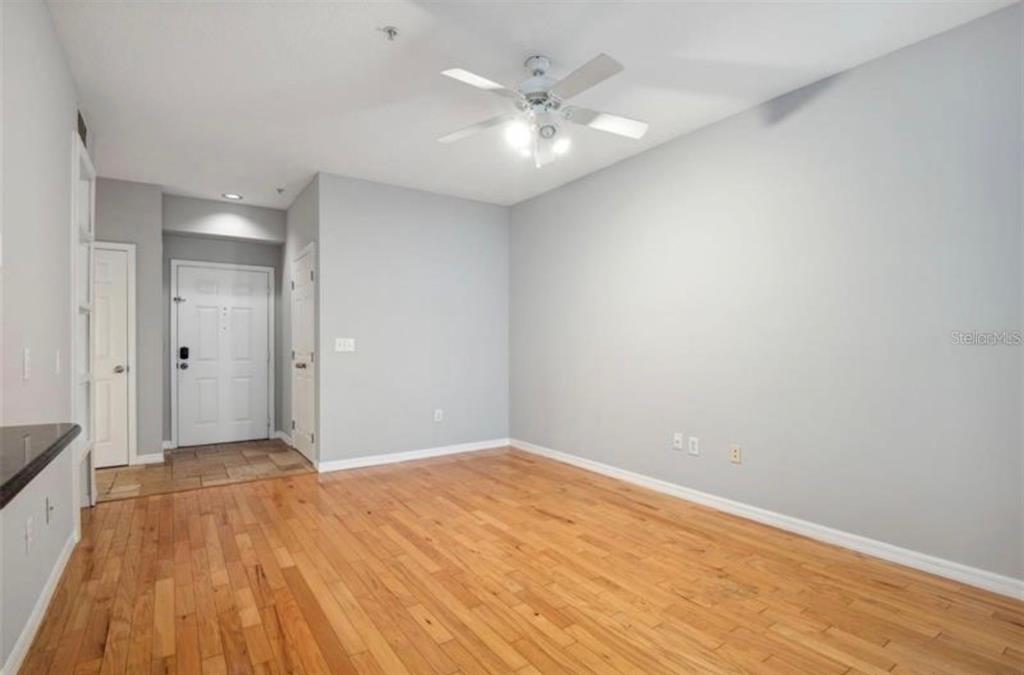An empty living room with hardwood floors, a ceiling fan, and a kitchen pass-through window — 1810 E PALM AVENUE UNIT 1205, TAMPA, FL