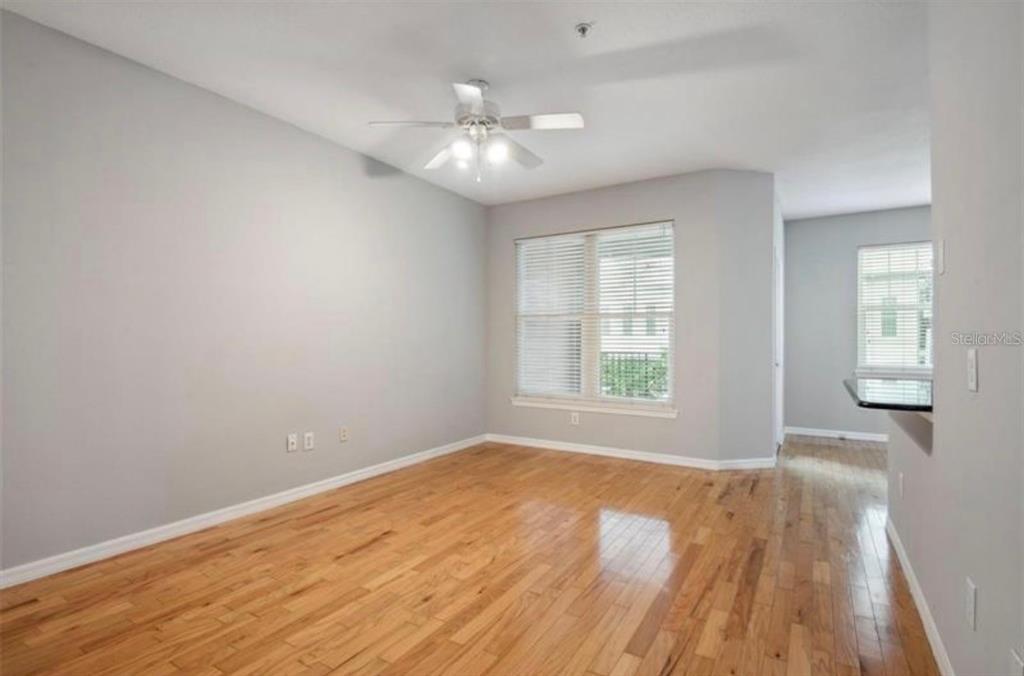 An empty room with light gray walls, hardwood floors, a ceiling fan, and two windows — 1810 E PALM AVENUE UNIT 1205, TAMPA, FL