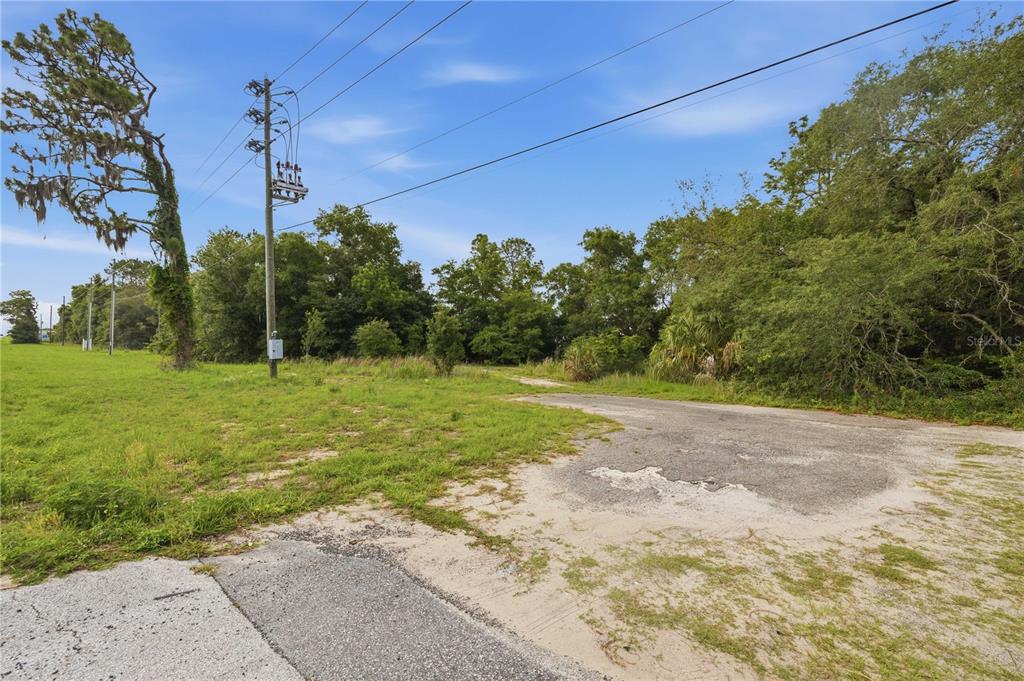 A view of a grassy lot with a paved driveway and utility poles — TBD CR-25, BELLEVIEW, FL