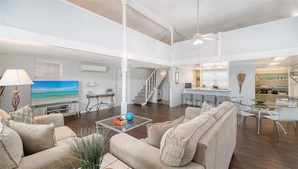 A living room with vaulted ceilings, a staircase, and an open kitchen with a breakfast bar — 3453 GULF OF MEXICO DRIVE UNIT 200, LONGBOAT KEY, FL