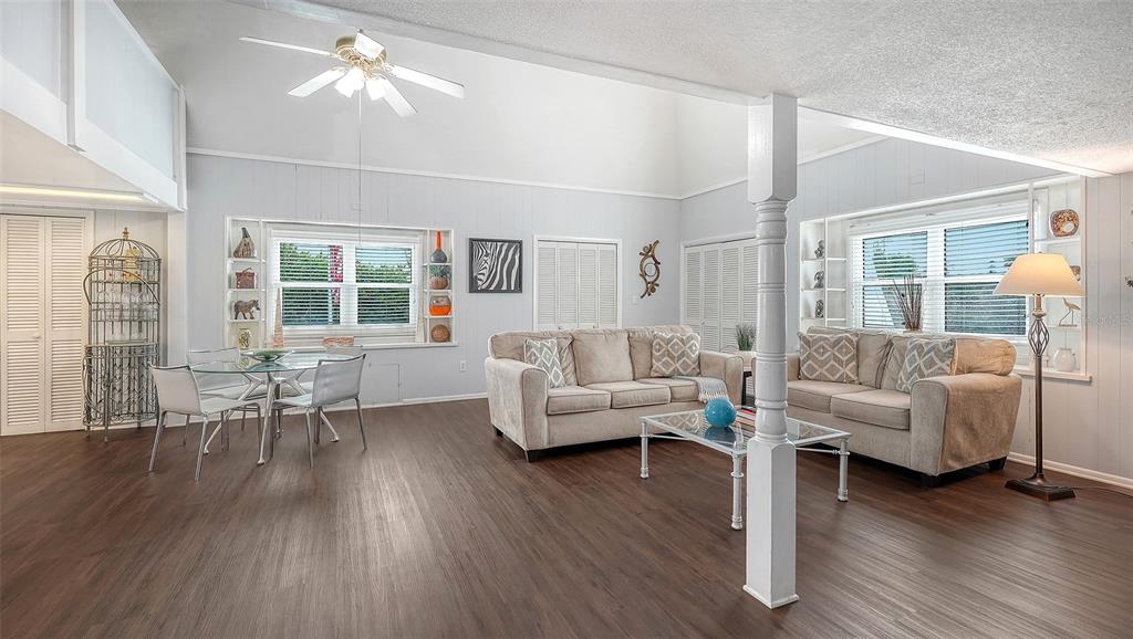 A living and dining area with vaulted ceilings, wood-look flooring, and two beige sofas — 3453 GULF OF MEXICO DRIVE UNIT 200, LONGBOAT KEY, FL