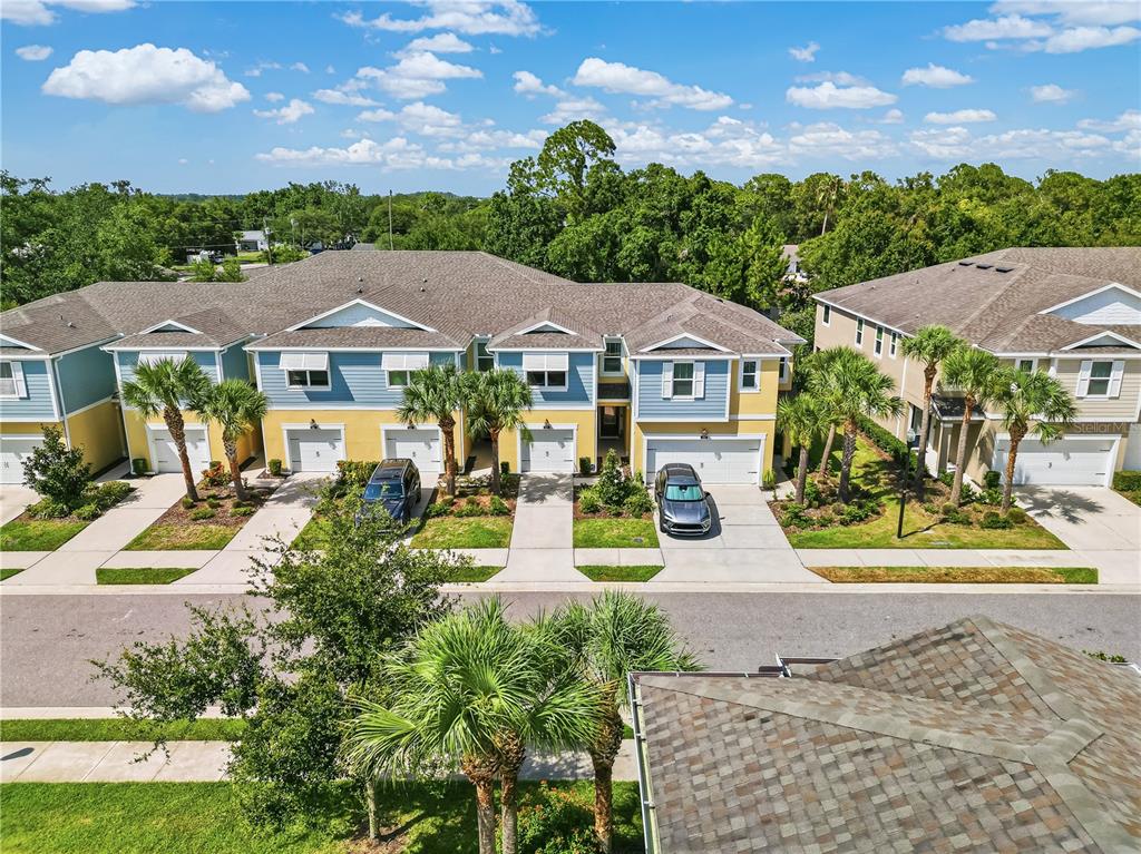 An aerial view shows a row of multi-story townhouses with garages and palm trees — 1309 SUNSET WIND LOOP, OLDSMAR, FL
