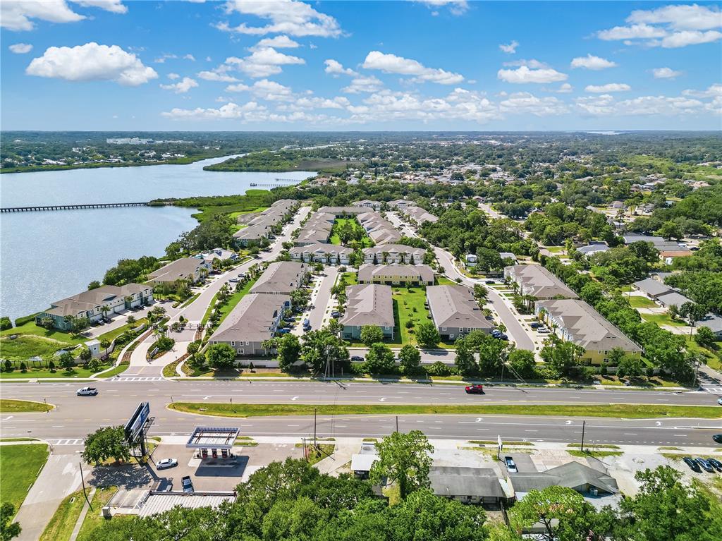 An aerial view shows a multi-family residential complex situated next to a large lake — 1309 SUNSET WIND LOOP, OLDSMAR, FL