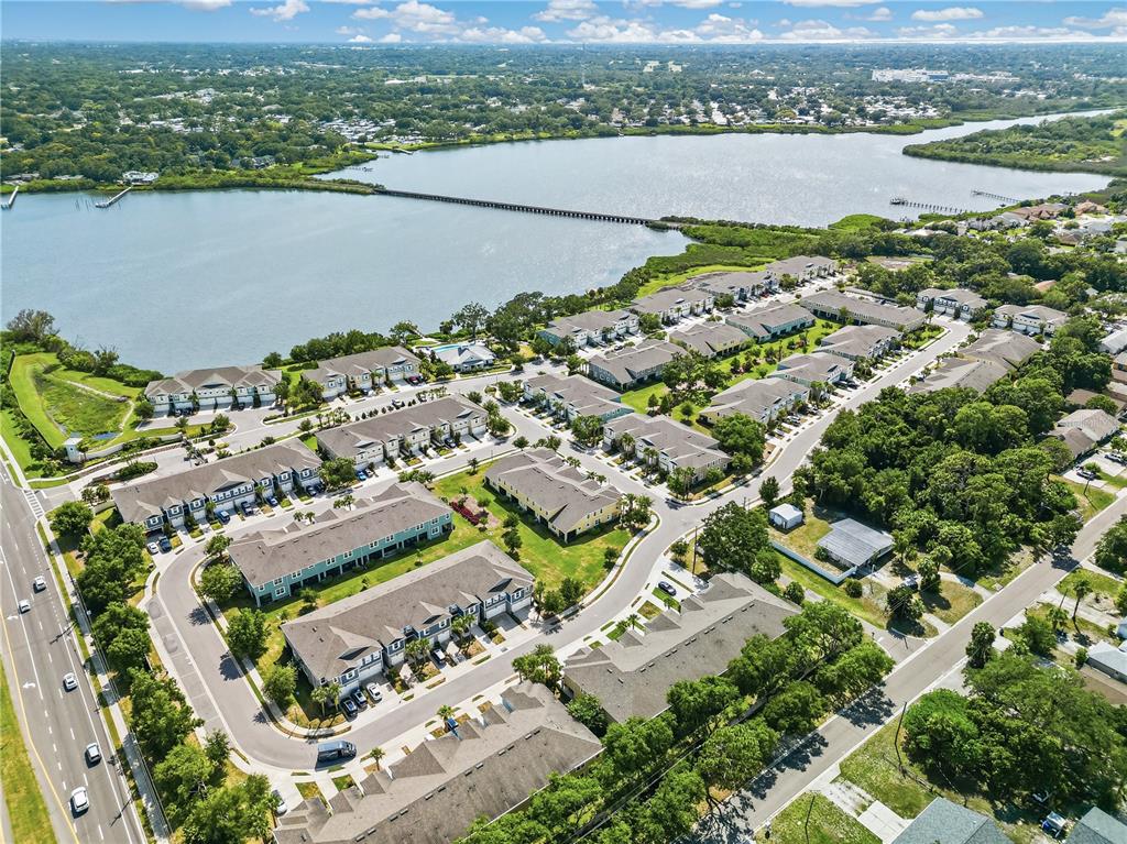 An aerial view shows a residential complex with multi-family buildings situated near a large lake — 1309 SUNSET WIND LOOP, OLDSMAR, FL