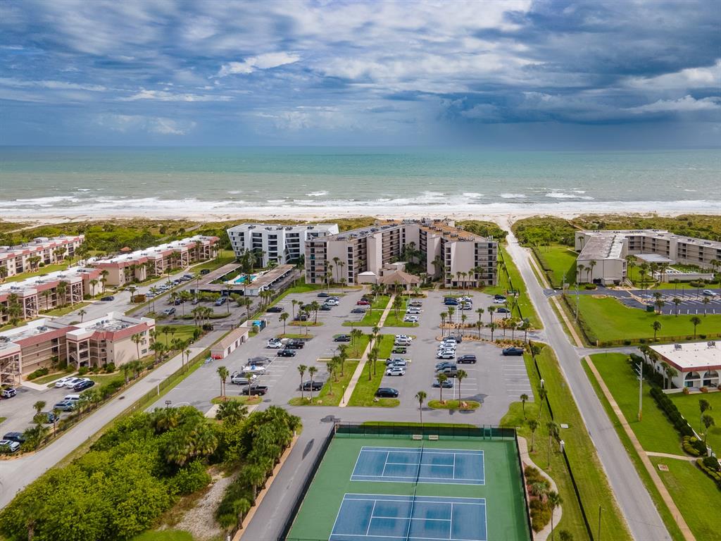 An aerial view shows a beachfront apartment complex with a parking lot and tennis courts — 2 DONDANVILLE ROAD UNIT 112, ST AUGUSTINE, FL