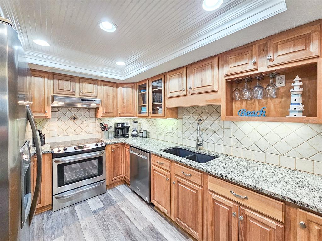 A kitchen features wood cabinets, granite countertops, stainless steel appliances, and a tiled backsplash — 2 DONDANVILLE ROAD UNIT 112, ST AUGUSTINE, FL