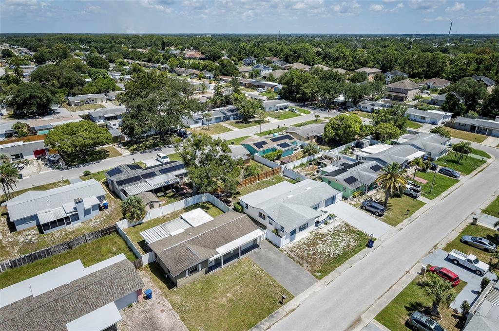 An aerial view shows a suburban neighborhood with single-story houses, paved streets, and green trees — 3246 BROOKFIELD DRIVE, HOLIDAY, FL