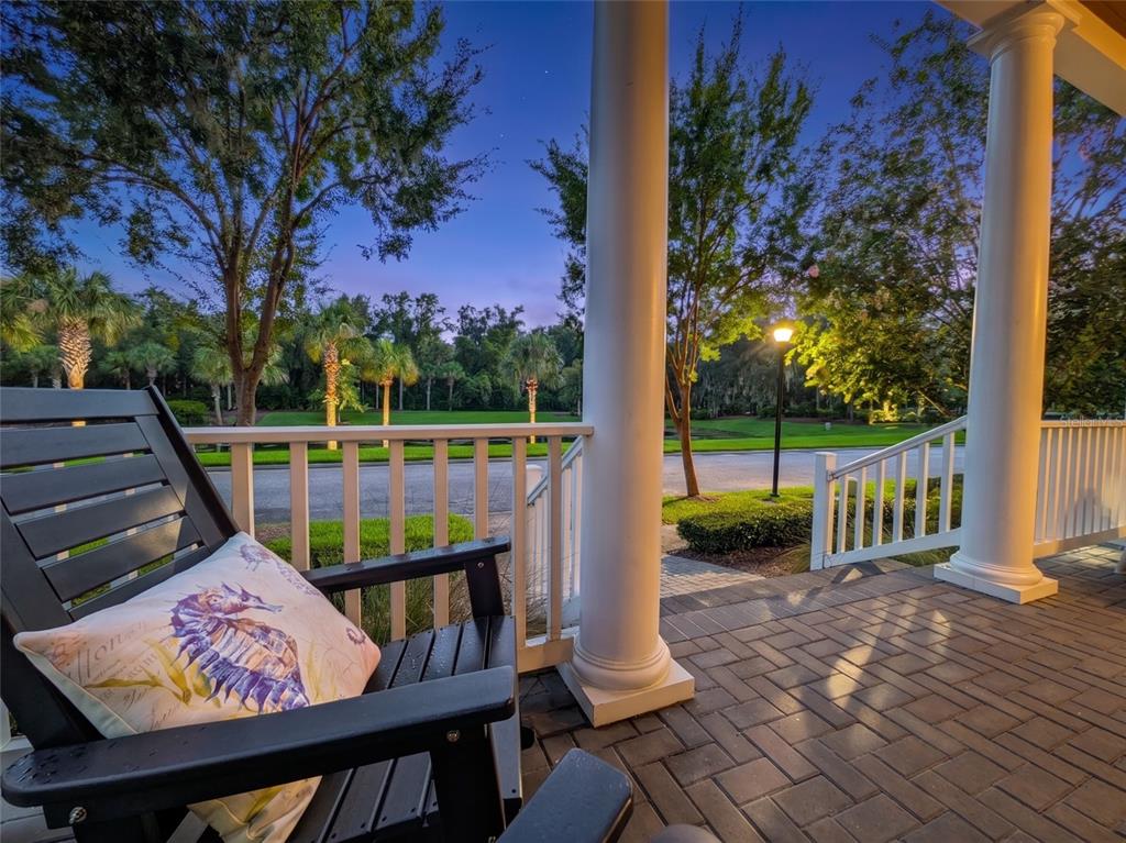 A view from a paved porch featuring a black chair and white columns overlooking trees — 305 STERNWHEEL DRIVE, ST JOHNS, FL