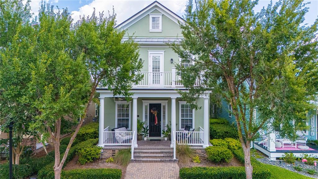 A two-story green house with a front porch, balcony, and landscaped yard — 305 STERNWHEEL DRIVE, ST JOHNS, FL