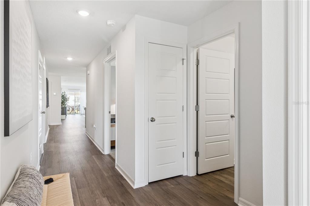 A hallway with wood-look flooring leads to an open living area with white interior doors — 1142 AMBER WAVES COURT, LAKE WALES, FL