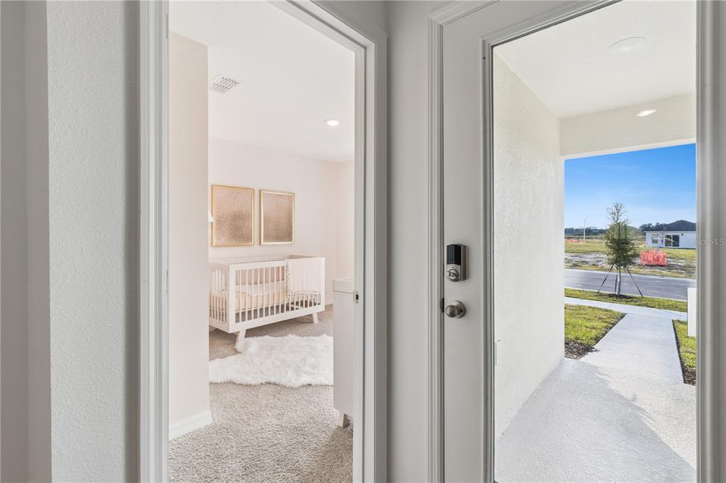 A view through an open door shows a nursery with a crib and a front porch — 1142 AMBER WAVES COURT, LAKE WALES, FL