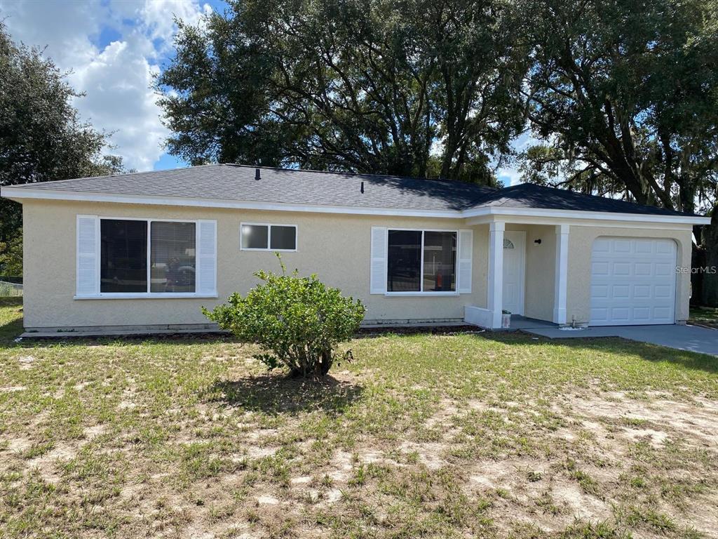 A single-story house with light-colored stucco walls, a dark roof, and a one-car garage — 5 HICKORY TRACK RUN, OCALA, FL