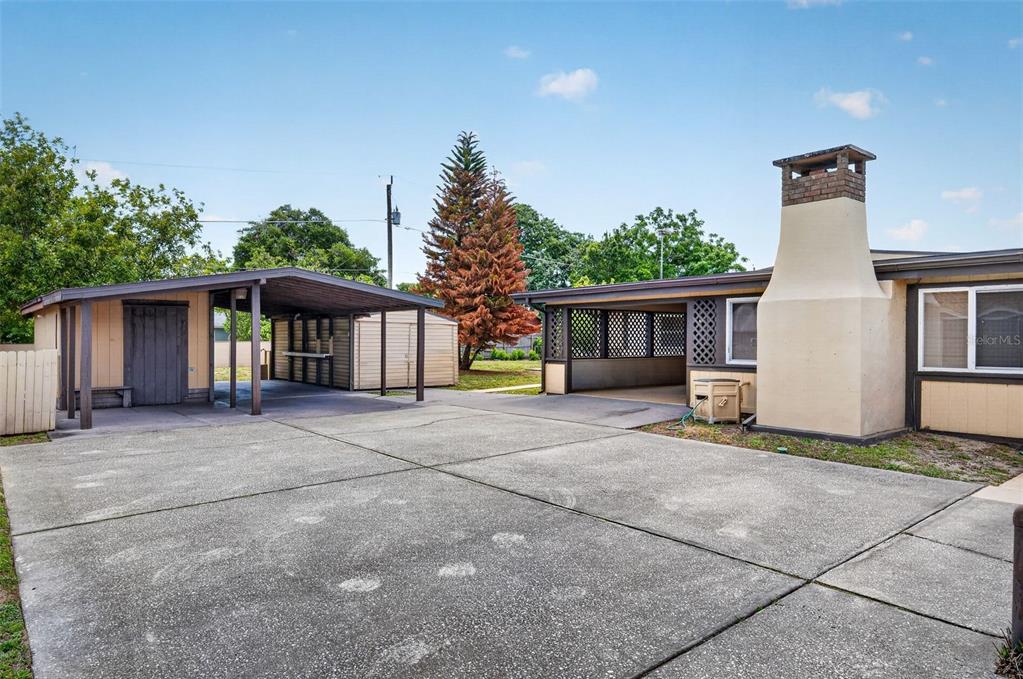 A concrete driveway leads to a house with a carport and a large brick chimney — 1961 CAROLINA AVENUE, ORMOND BEACH, FL