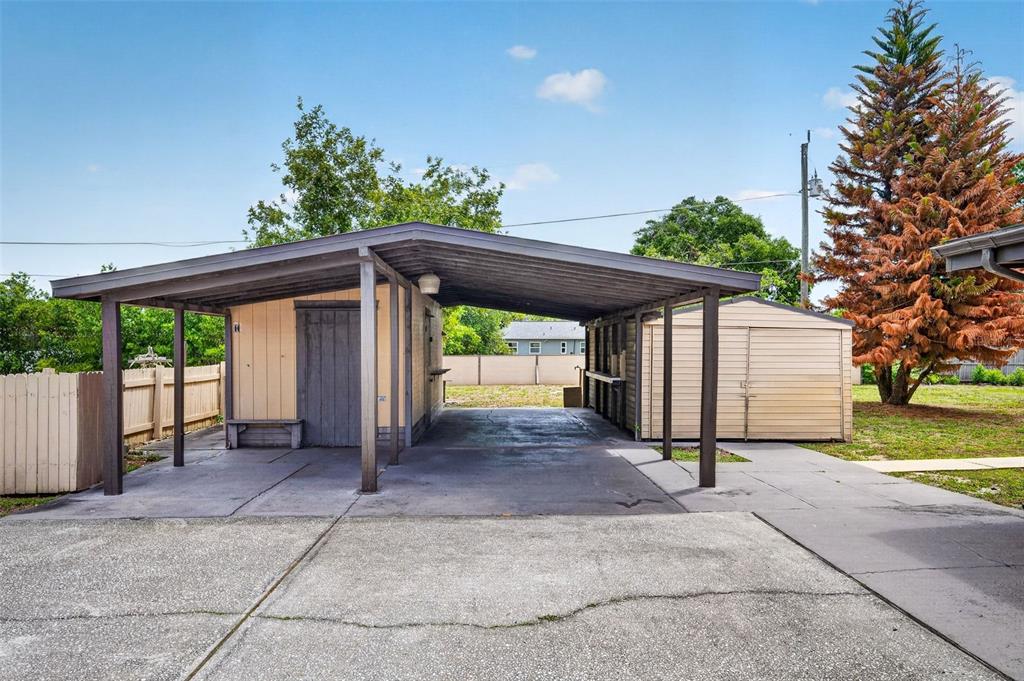A concrete driveway leads to a covered carport attached to a small storage shed — 1961 CAROLINA AVENUE, ORMOND BEACH, FL