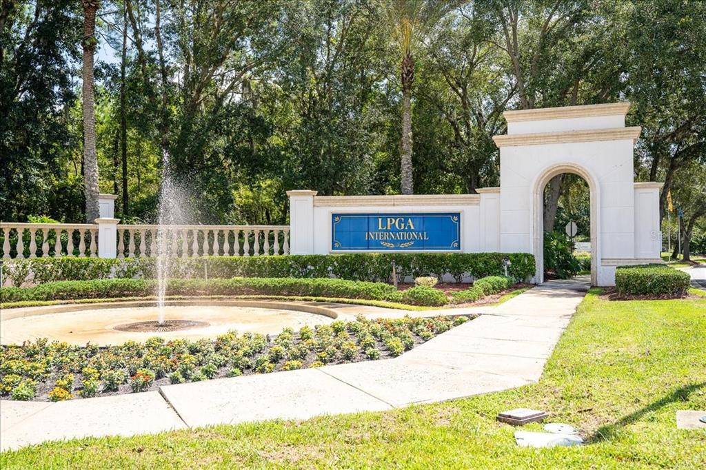 A fountain sits in front of a white arched entrance sign for LPGA International — 101 MCGILL CIRCLE, DAYTONA BEACH, FL