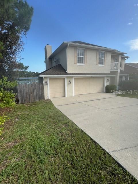 A two-story beige house features a two-car garage and a wooden fence near water — 386 HAVERSHAM ROAD, DELTONA, FL