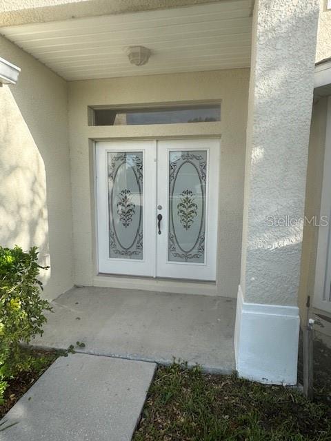 A white double front door with decorative glass inserts sits under a covered entryway — 386 HAVERSHAM ROAD, DELTONA, FL