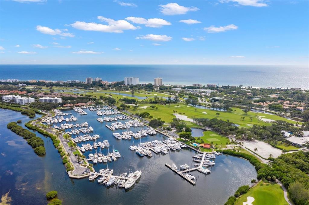 An aerial view shows a marina filled with boats adjacent to a golf course — 2600 HARBOURSIDE DR UNIT B-06, LONGBOAT KEY, FL