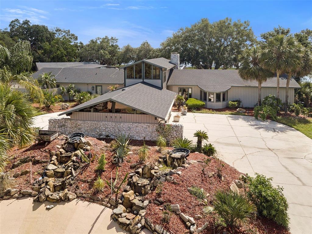 An aerial view shows a sprawling house with a stone wall and a rock garden — 5575 ALLIGATOR LAKE ROAD, ST CLOUD, FL