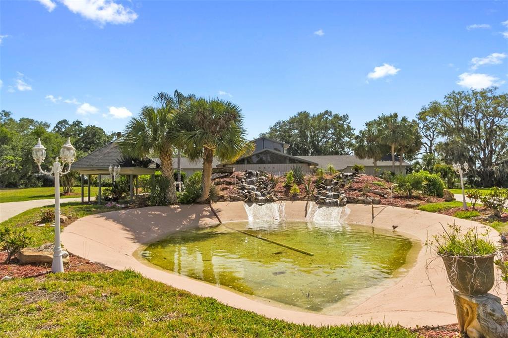A backyard pond with a stone waterfall feature sits in front of a house — 5575 ALLIGATOR LAKE ROAD, ST CLOUD, FL