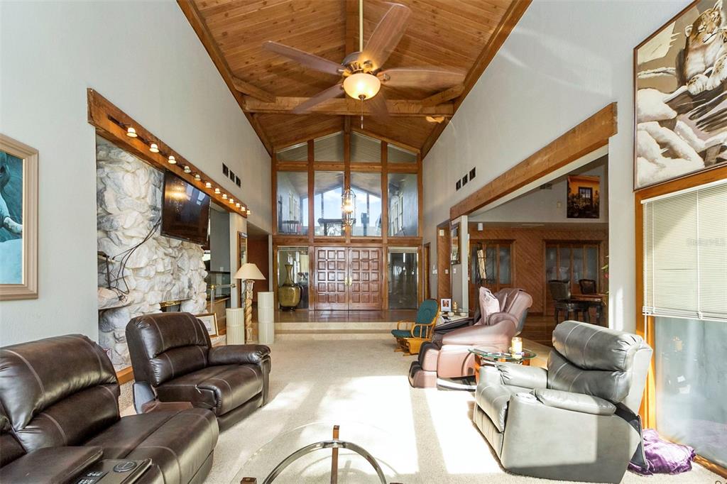 A living room features a vaulted wood-paneled ceiling, a stone fireplace, and brown leather recliners — 5575 ALLIGATOR LAKE ROAD, ST CLOUD, FL