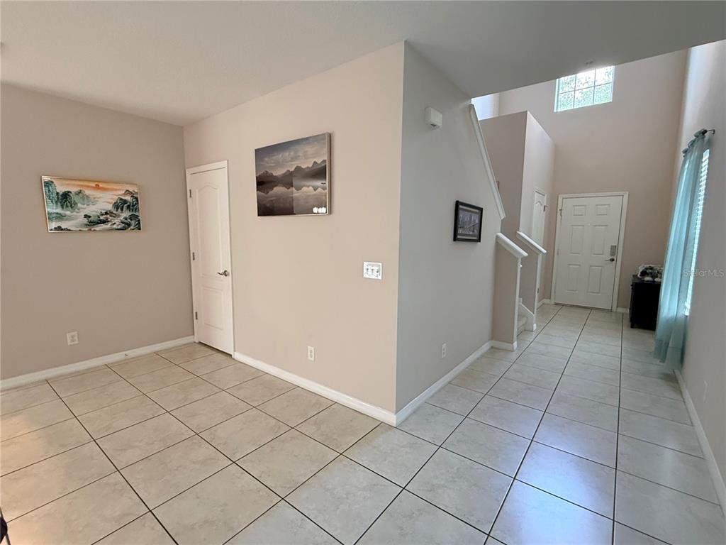 An entryway with tiled floors, a staircase, and a front door under a high ceiling — 2084 WATER TUPELO WAY, OCOEE, FL