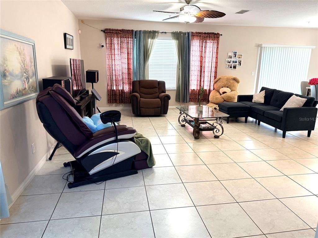 A living room features tile flooring, a massage chair, a sofa, and a large teddy bear — 2084 WATER TUPELO WAY, OCOEE, FL